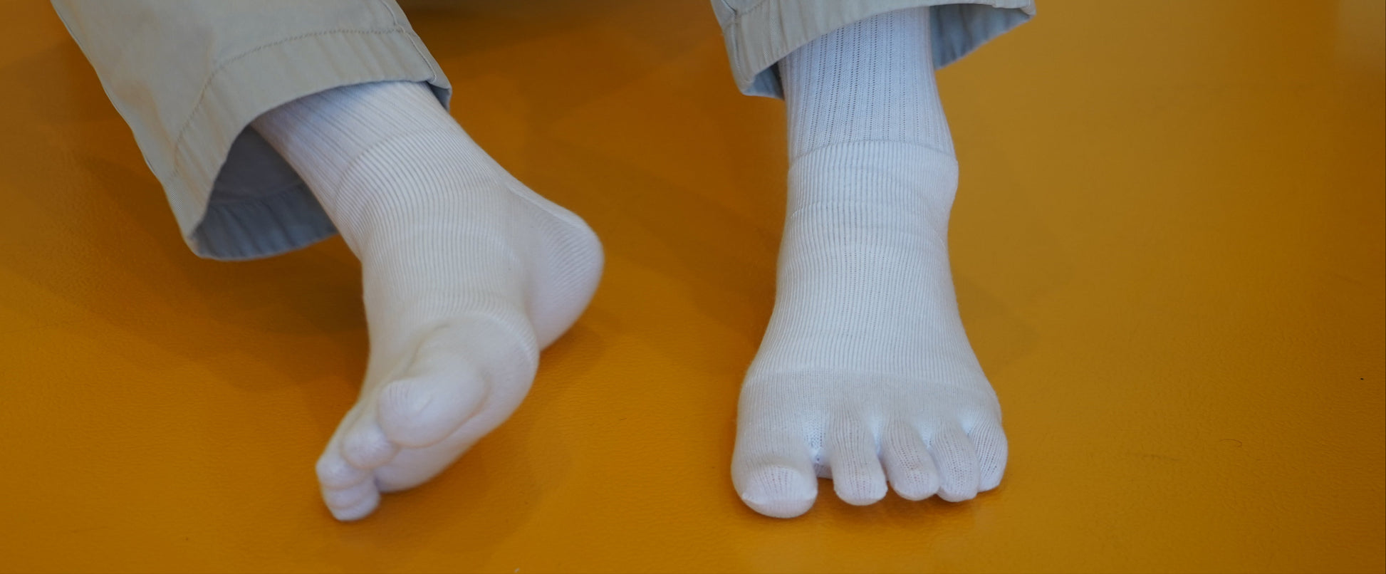 Person wearing beige pants and white toe socks on a yellow floor.