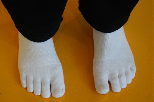 White toe-separated socks on a yellow background
